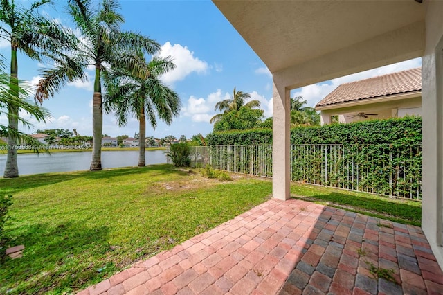 view of patio with a water view, fence, and ceiling fan