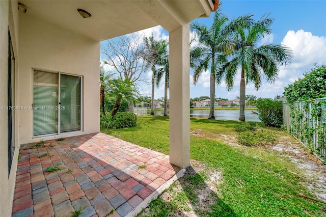 view of patio featuring a water view and fence