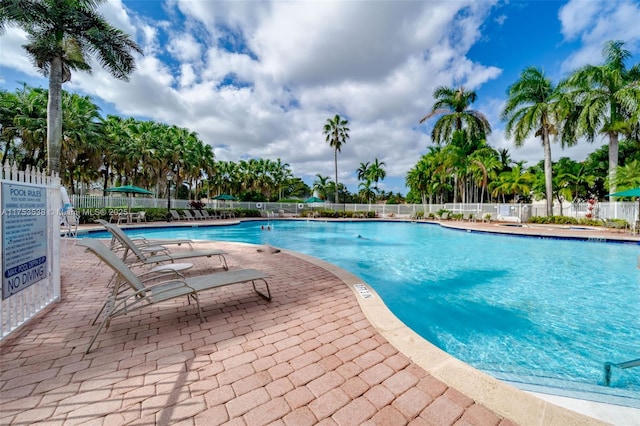 community pool with a patio and fence