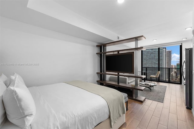 bedroom featuring freestanding refrigerator, light wood finished floors, and recessed lighting