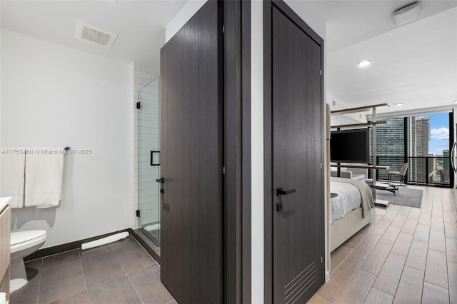 ensuite bathroom with a stall shower, baseboards, visible vents, ensuite bathroom, and expansive windows