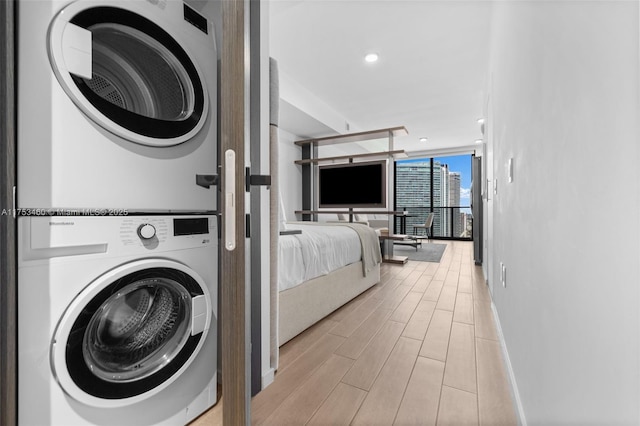 laundry room featuring wood tiled floor, baseboards, stacked washer / drying machine, and recessed lighting