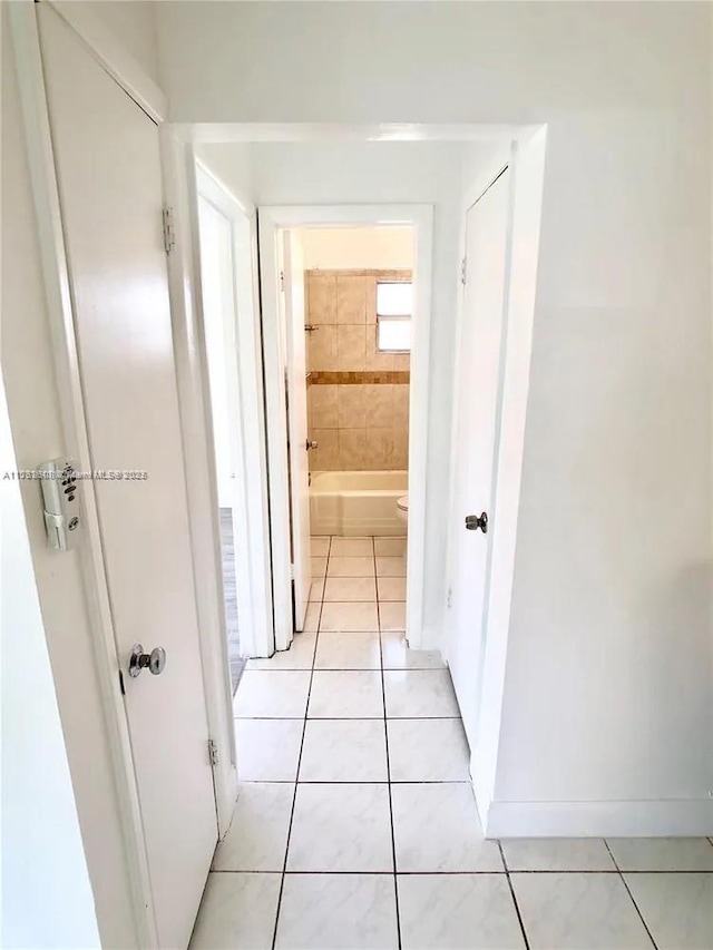 hall featuring light tile patterned floors and baseboards