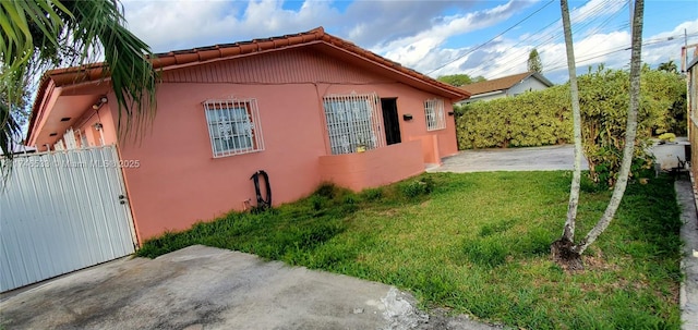 view of side of property with a patio area, a lawn, fence, and stucco siding