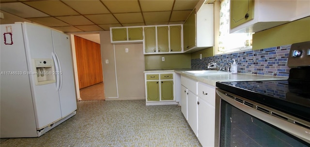 kitchen featuring a sink, light countertops, white fridge with ice dispenser, tasteful backsplash, and stainless steel range with electric stovetop