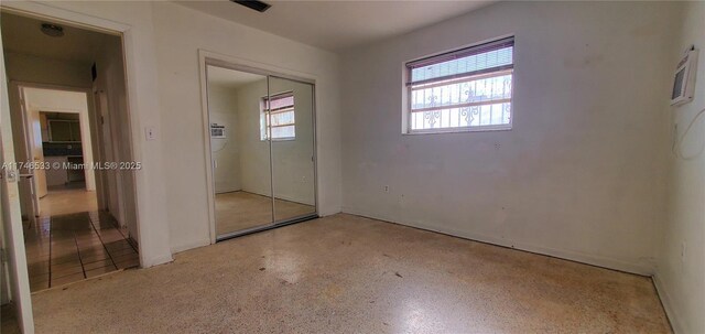 unfurnished bedroom featuring a closet, multiple windows, and speckled floor