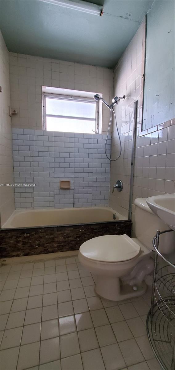 full bath featuring shower / bathtub combination, tile patterned floors, toilet, and tile walls