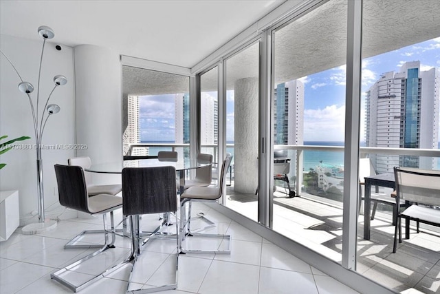 tiled dining room featuring expansive windows, a water view, and a city view