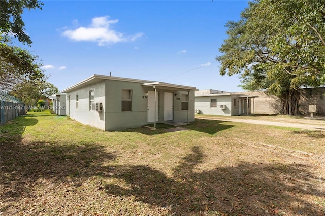 back of property with a yard, fence, cooling unit, and stucco siding