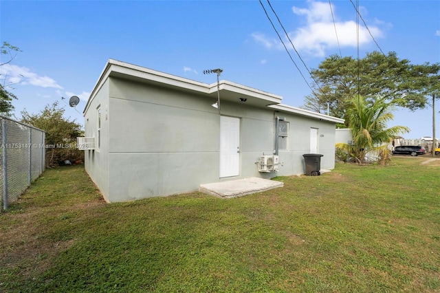 back of property featuring stucco siding, a lawn, and fence