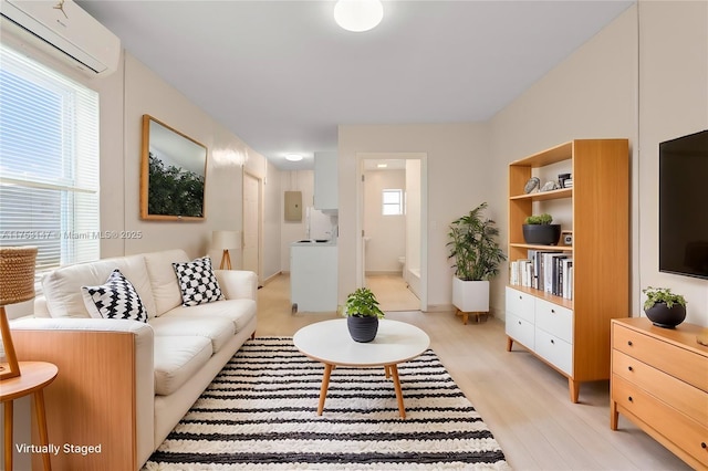 living area featuring light wood finished floors, plenty of natural light, built in shelves, and a wall mounted air conditioner