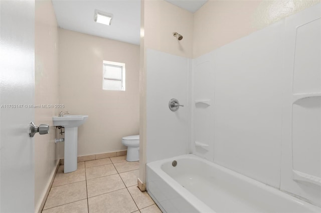 bathroom with baseboards, toilet, tile patterned floors, shower / bathtub combination, and a sink