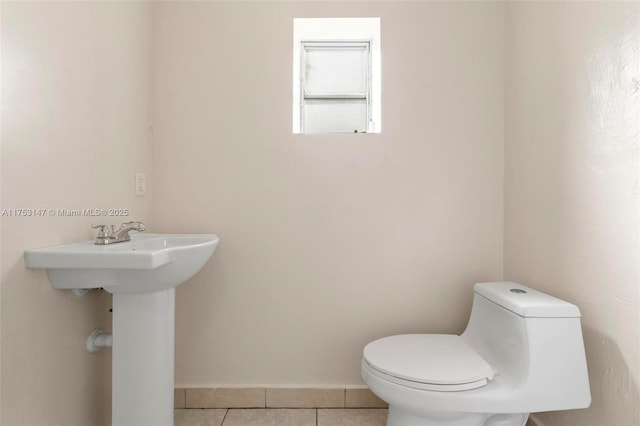 bathroom with baseboards, toilet, and tile patterned floors