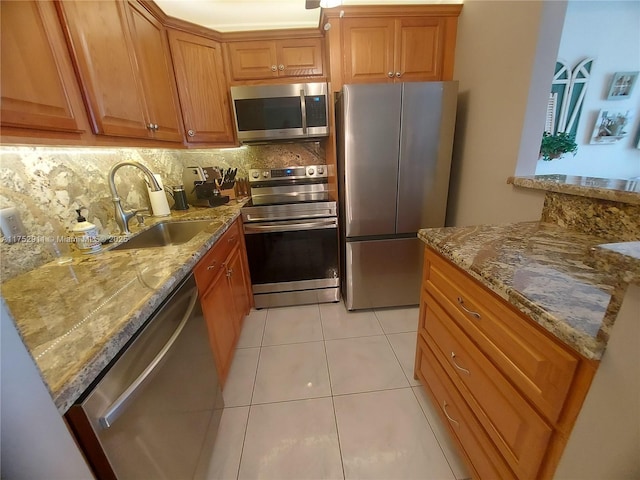 kitchen featuring a sink, light stone countertops, backsplash, and stainless steel appliances