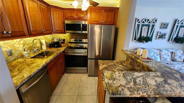 kitchen with light tile patterned floors, stainless steel appliances, backsplash, stone countertops, and a sink