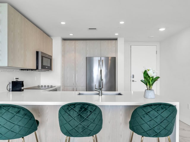 2000 Metropica Way Unit 1507, Sunrise, FL 33323 - kitchen featuring stainless steel appliances, light brown cabinetry, light countertops, and a breakfast bar