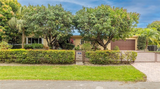 obstructed view of property with an attached garage, fence, decorative driveway, and stucco siding