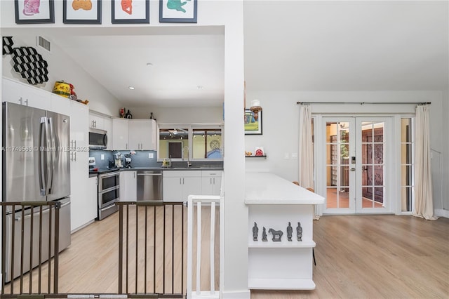 kitchen featuring visible vents, white cabinets, appliances with stainless steel finishes, french doors, and light wood-style floors