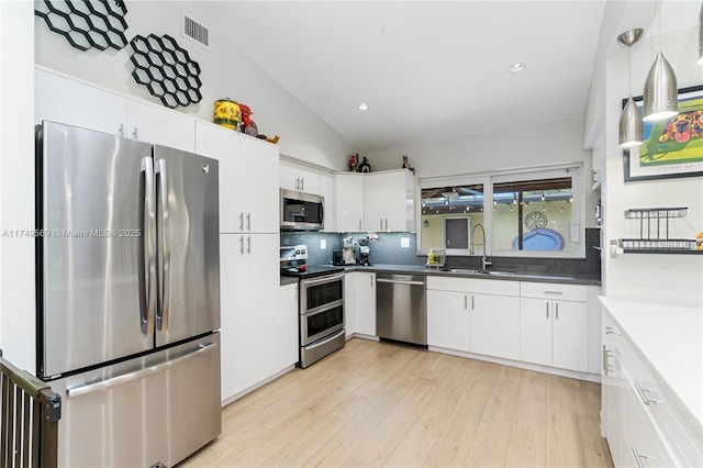 kitchen featuring stainless steel appliances, a sink, visible vents, white cabinetry, and light wood-type flooring