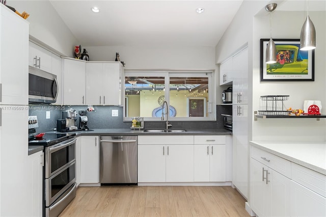 kitchen featuring appliances with stainless steel finishes, light wood-type flooring, a sink, and decorative backsplash