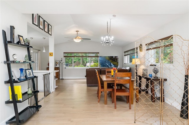 dining space with vaulted ceiling, ceiling fan with notable chandelier, and light wood-style flooring