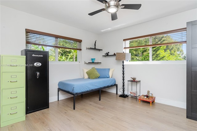 living area featuring light wood-style floors, a healthy amount of sunlight, baseboards, and a ceiling fan