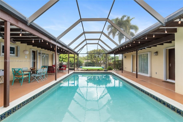 outdoor pool featuring glass enclosure and a patio