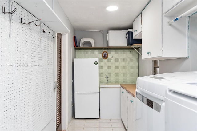 laundry area with washer / clothes dryer and light tile patterned floors