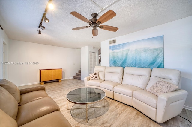 living area with visible vents, stairway, a ceiling fan, a textured ceiling, and wood finished floors