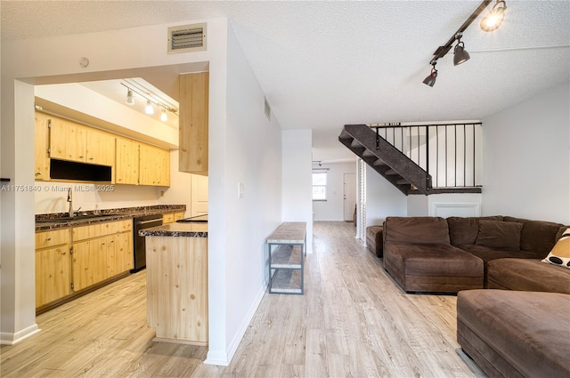 kitchen featuring dark countertops, dishwashing machine, a sink, and light brown cabinetry