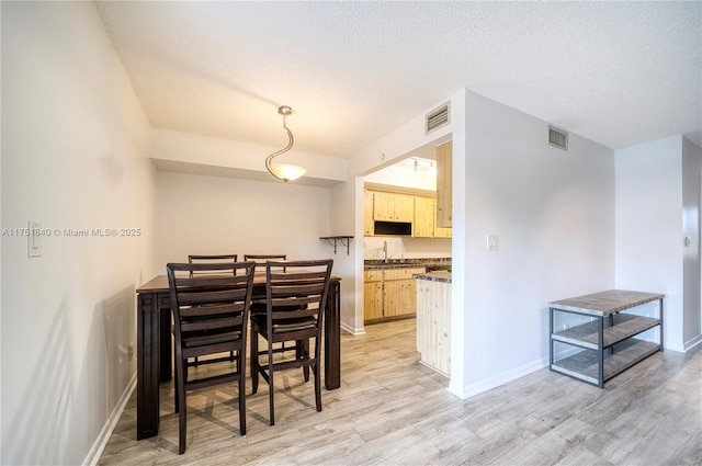 dining room featuring light wood-type flooring, visible vents, and baseboards