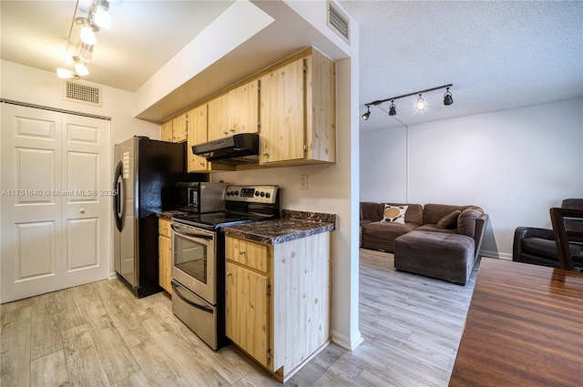 kitchen featuring stainless steel appliances, dark countertops, light brown cabinetry, light wood-style floors, and under cabinet range hood