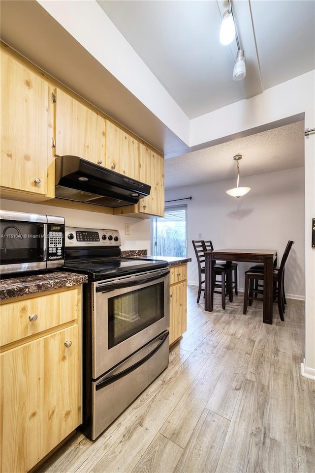 kitchen with stainless steel appliances, dark countertops, light brown cabinetry, light wood-type flooring, and under cabinet range hood