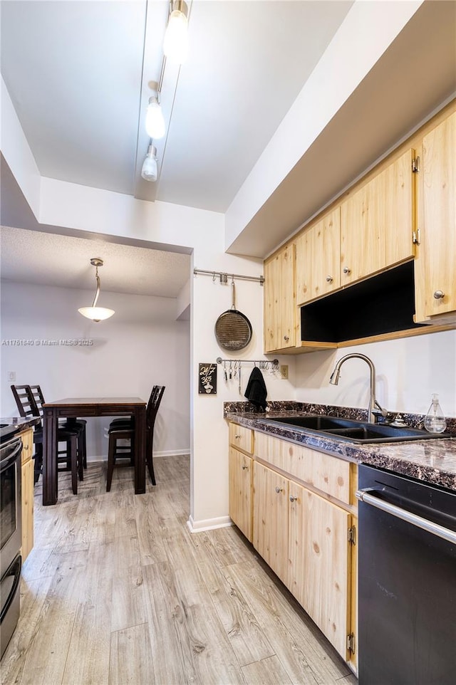 kitchen featuring light wood finished floors, black dishwasher, dark countertops, light brown cabinetry, and a sink