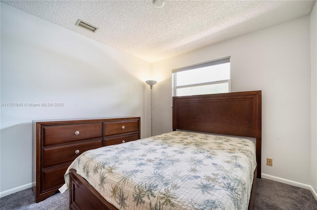 bedroom with baseboards, a textured ceiling, visible vents, and carpet flooring