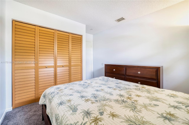 bedroom with a textured ceiling, carpet floors, a closet, and visible vents