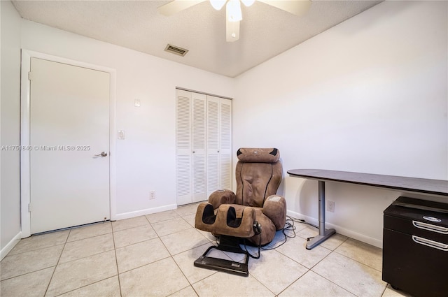 living area with light tile patterned floors, a textured ceiling, visible vents, and baseboards