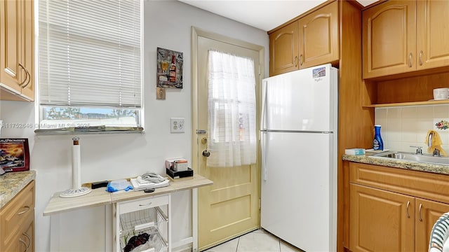 kitchen featuring tasteful backsplash, freestanding refrigerator, a healthy amount of sunlight, and a sink