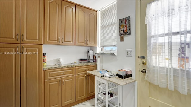 kitchen featuring light tile patterned floors and light stone counters