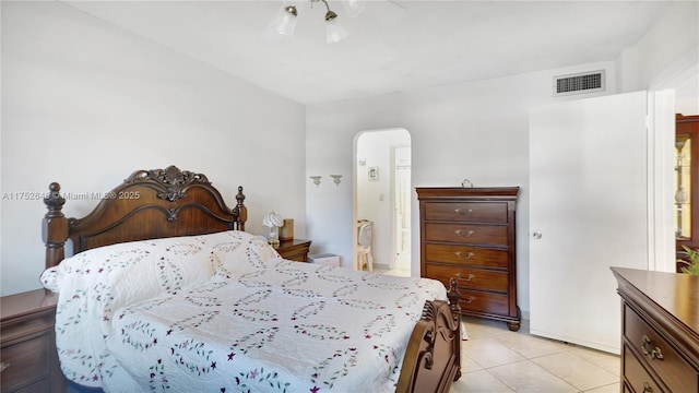 bedroom with arched walkways, light tile patterned flooring, and visible vents