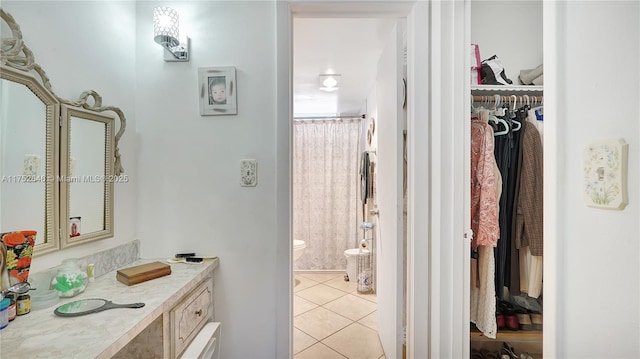 full bath featuring a shower with shower curtain, toilet, tile patterned floors, a spacious closet, and vanity