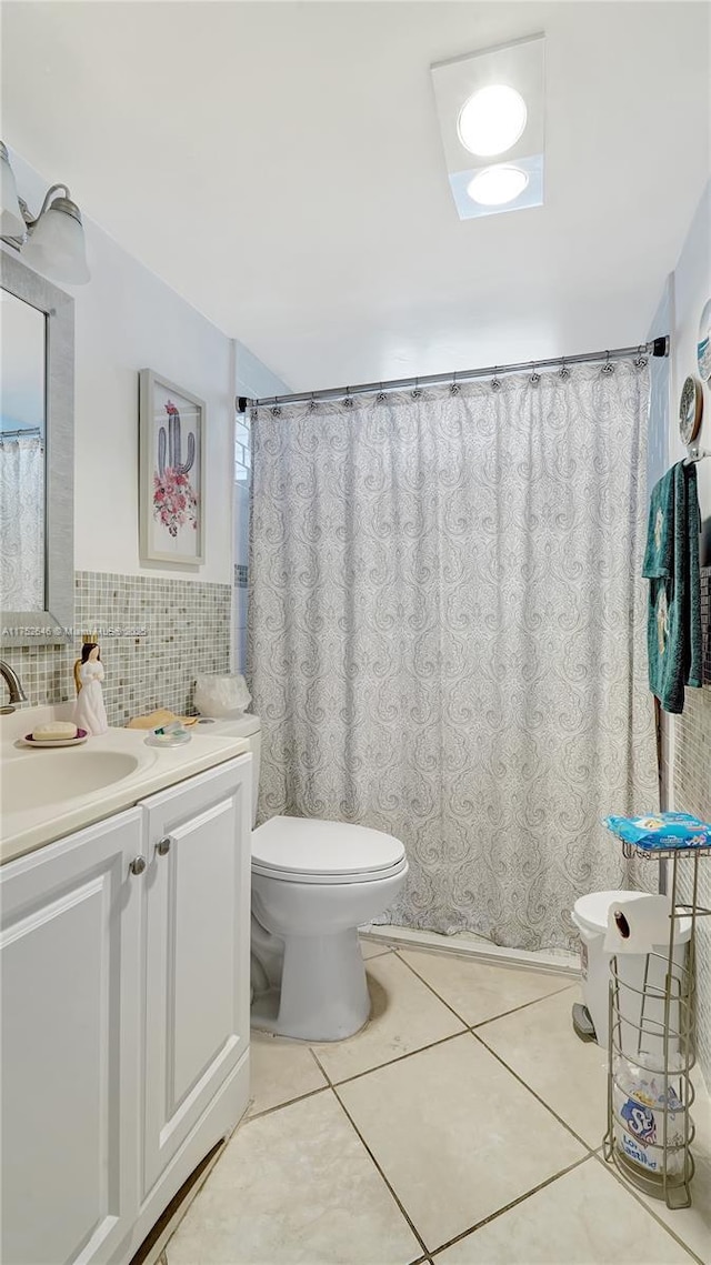 bathroom featuring toilet, vanity, tile walls, and tile patterned floors