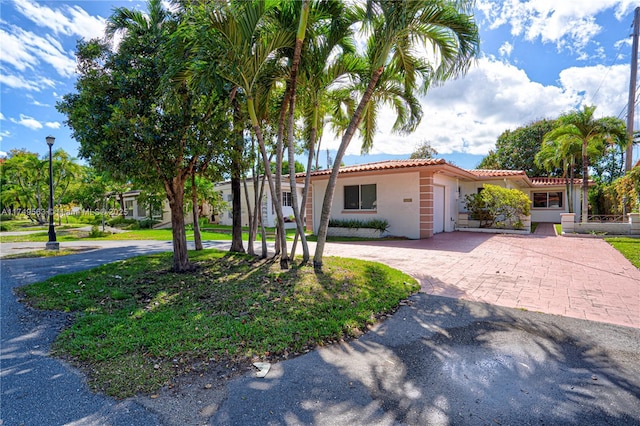 view of front of house featuring curved driveway, a tiled roof, and stucco siding