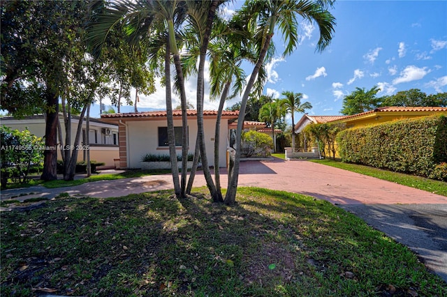 mediterranean / spanish-style home featuring decorative driveway, a tiled roof, and stucco siding