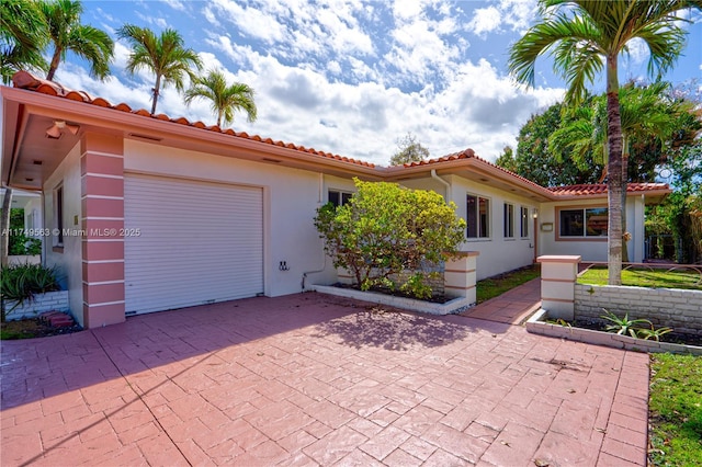 view of front facade featuring a garage, a tile roof, and stucco siding