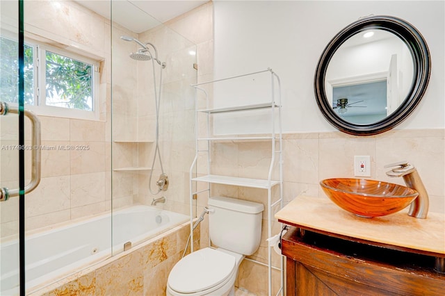 bathroom with tiled shower / bath combo, toilet, tile walls, and vanity