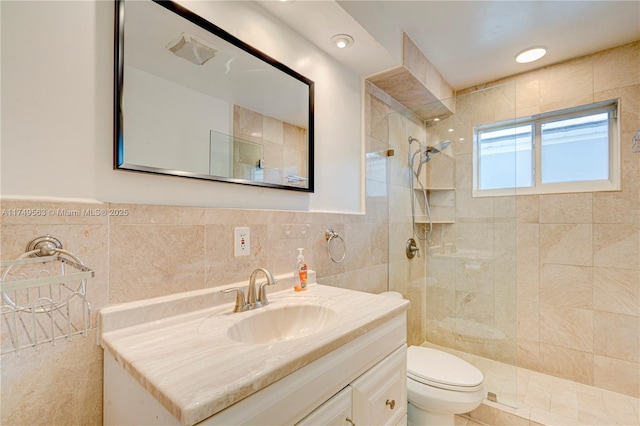 bathroom featuring wainscoting, toilet, walk in shower, vanity, and tile walls