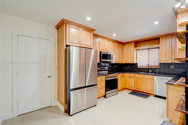 kitchen featuring tasteful backsplash, dark stone countertops, stainless steel appliances, a sink, and recessed lighting