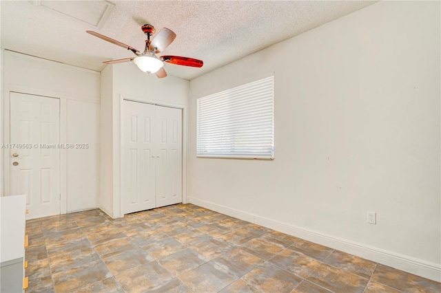 unfurnished bedroom featuring baseboards, ceiling fan, stone finish flooring, a textured ceiling, and a closet