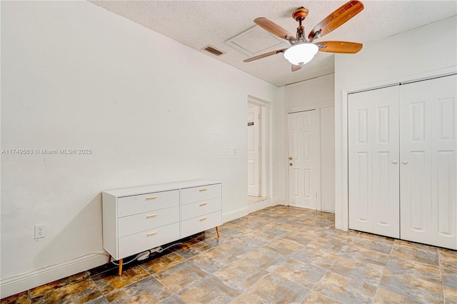 unfurnished bedroom with stone finish flooring, visible vents, a textured ceiling, and baseboards